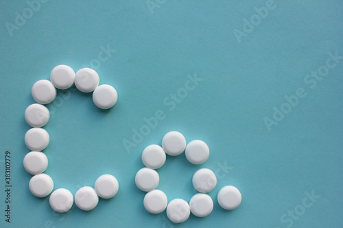 Calcium supplement pills in shape of Ca element on blue background with copy space.