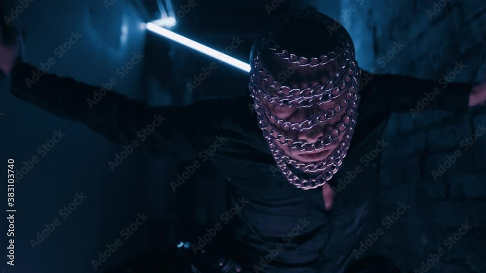 Sexy dancer man in the chain mask on the dark night club background. Filmed in fluorescent clothing under UV black light. Club party glamor style. Creative art