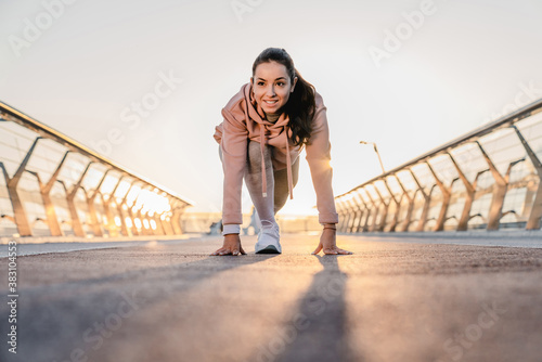 Young female athlete is going to run on the bridge with sunlight behind
