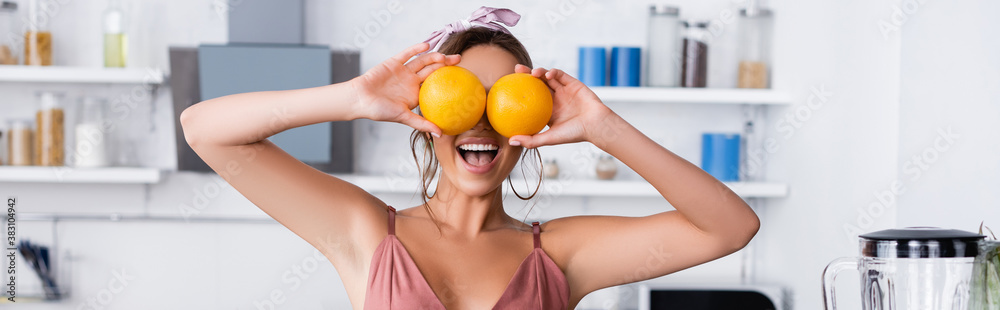Website header of woman holding oranges near eyes at home Website header of woman holding oranges near eyes at home