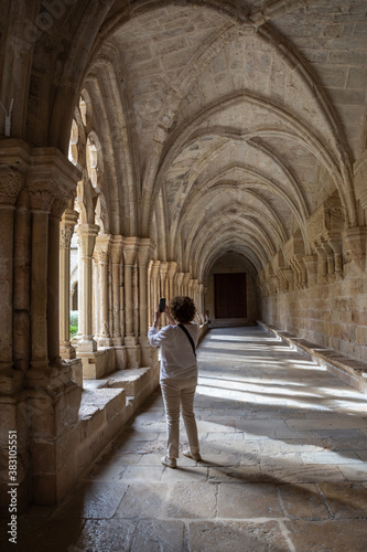 View of the cloister of the Poblet monastery with a woman on her back taking a photo with her smartphone  in vertical