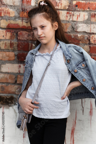 portrait of a beautiful teenage girl posing against a brick wall