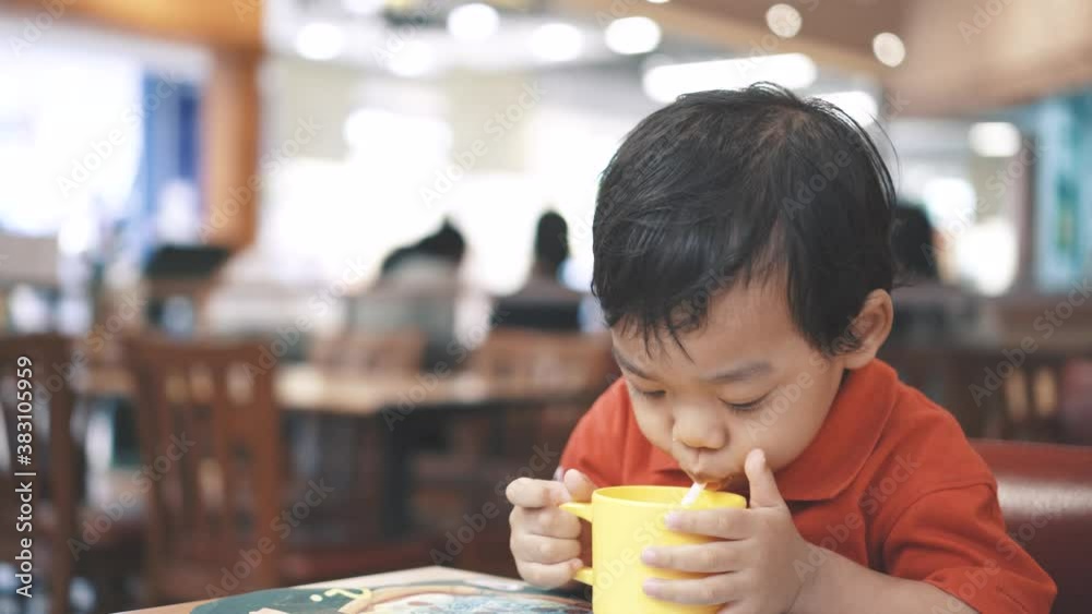 The boy take a cup of water and drink it then hold straw up and suck water in a straw