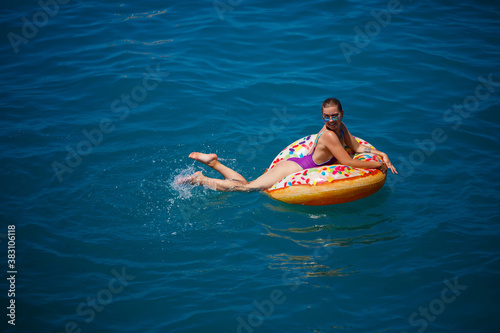 Beautiful happy young woman in a swimsuit with an inflatable ring relaxing in the blue sea. Sunny day, seaside vacation, tourism © Дмитрий Ткачук