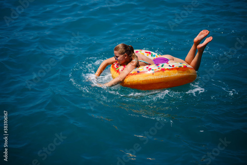 Beautiful happy young woman in a swimsuit with an inflatable ring relaxing in the blue sea. Sunny day, seaside vacation, tourism © Дмитрий Ткачук