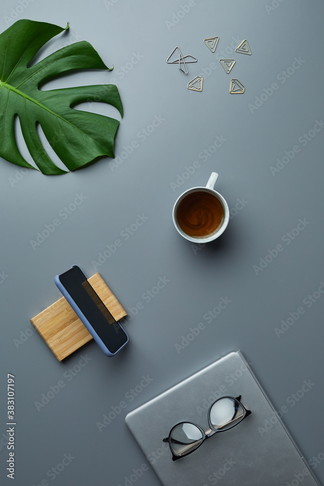 Above view flat lay of tropical leaf and business accessories over grey workplace background, copy space Above view flat lay of tropical leaf and business accessories over grey workplace background, copy space