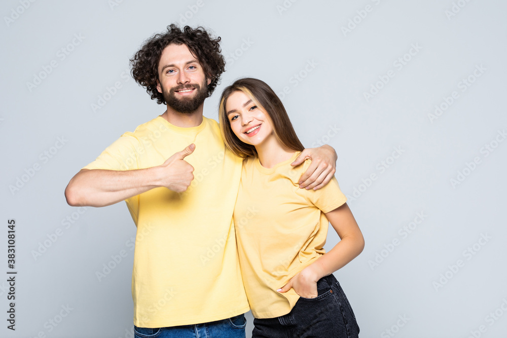 Attractive cheerful young lovers showing thumbs up isolated on gray background Attractive cheerful young lovers showing thumbs up isolated on gray background
