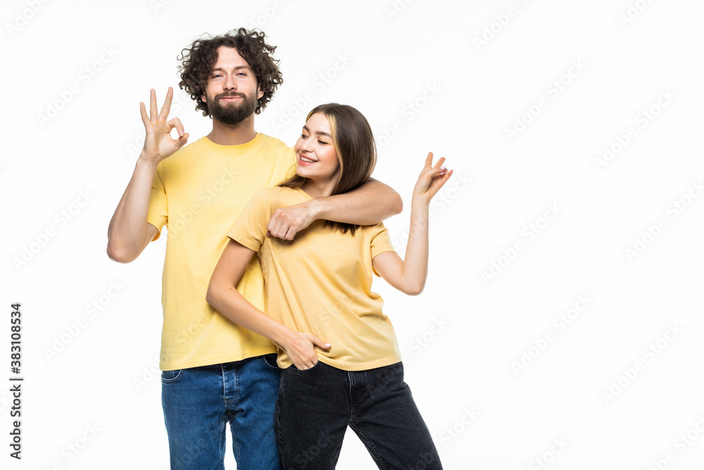 Portrait of a cheerful smiling couple hugging and showing okay gesture over gray background Portrait of a cheerful smiling couple hugging and showing okay gesture over gray background