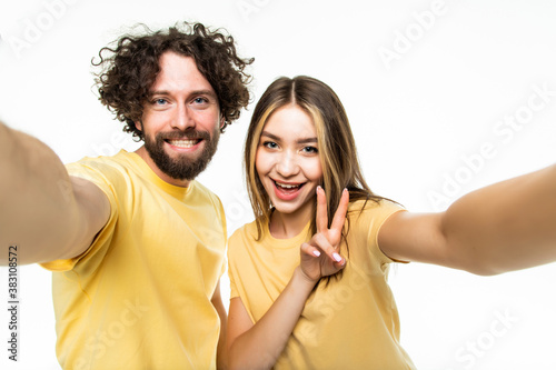 Funny couple showing tongues and gesturing v-sign while making selfie isolated on white background