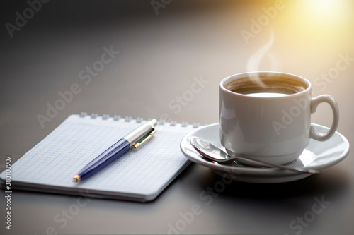 A cup of coffee with steam on the table. Planning and starting the day.