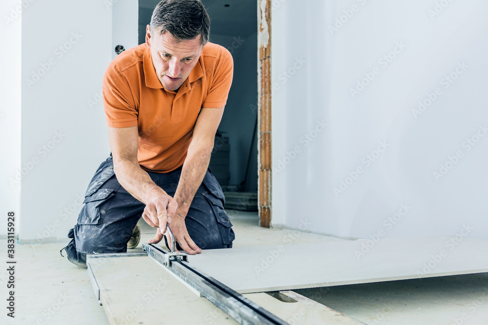 middle aged male worker installing large format tiles on wall