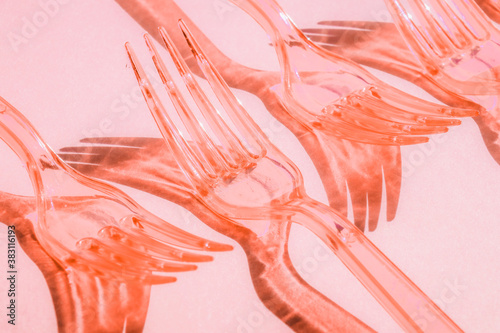 Abstract composition with shadows from plastic transparent forks on pink background