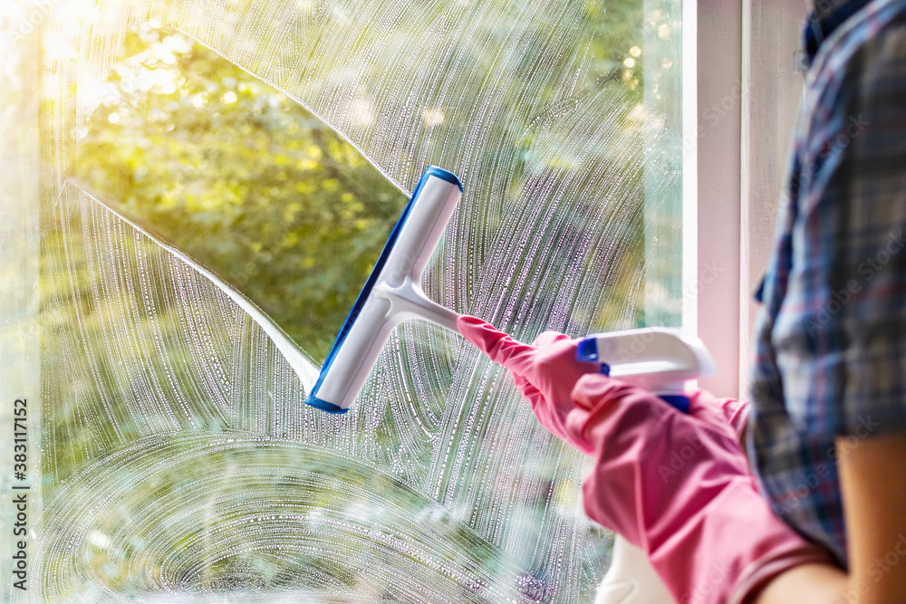 Как снять пластиковые окна чтобы помыть A woman clean a window pane with a squeegee and soap suds. Cleaning with a deter