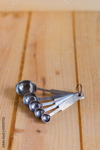 Measurement spoons set made of stainless steel against neutral wooden background