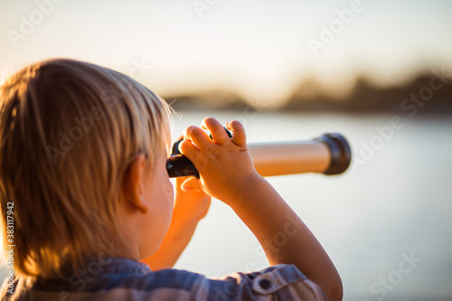 Quadro su tela Little boy looking through telescope outside.