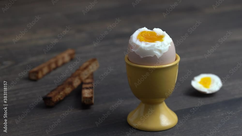 Soft boiled brown egg and toast bread in eggcup on wooden table background. Close up. Healthy breakfast