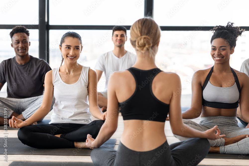 Group of multicultural man and woman practicing yoga with instructor in studio Group of multicultural man and woman practicing yoga with instructor in studio