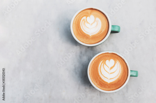 Two beautiful cups of cappuccino or latte on the table. Cosy coffee break concept. Flat-lay, top view. Copy space for your text.