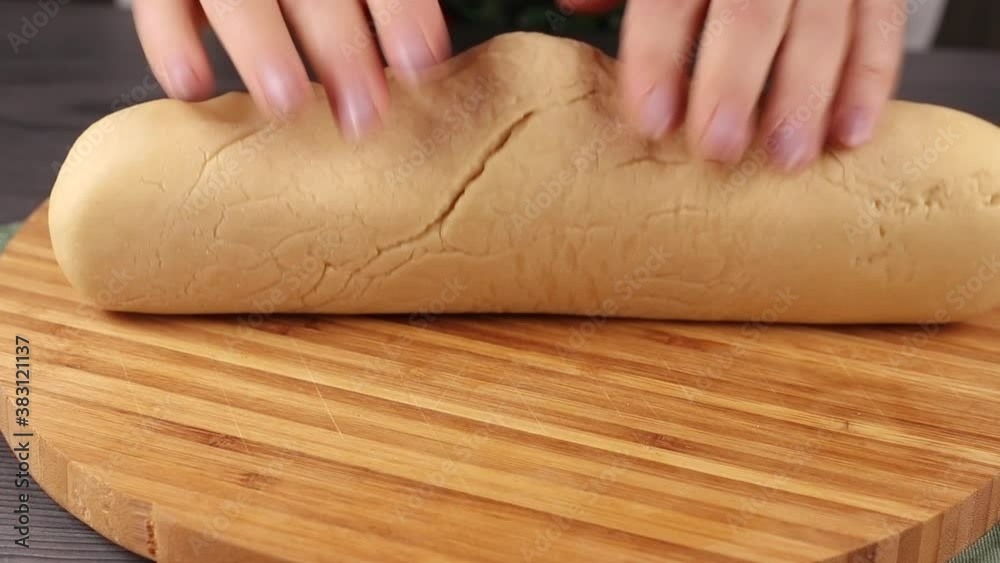 knead dough with hands on the wooden cutting board, slices of pastry close-up