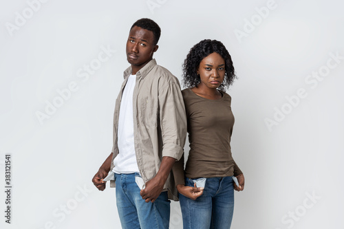 African american sad couple demonstrating empty pockets