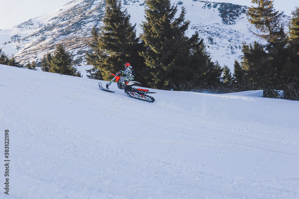Snowbike rider in mountain valley in beautiful snow powder. Snowdirt bike with splashes and trail. Snowmobile winter sport riding