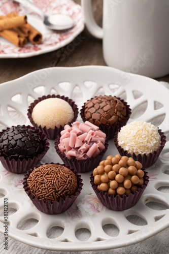 Typical brazilian brigadeiros, various flavors with spoon and coffee cup over wooden table
