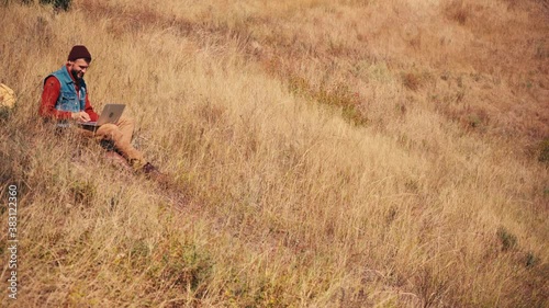 Wallpaper Mural Man in hat sitting and using laptop on hill Torontodigital.ca