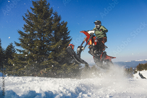 Snowbike rider in mountain valley in beautiful snow powder. Snowdirt bike with splashes and trail. Snowmobile winter sport riding photo