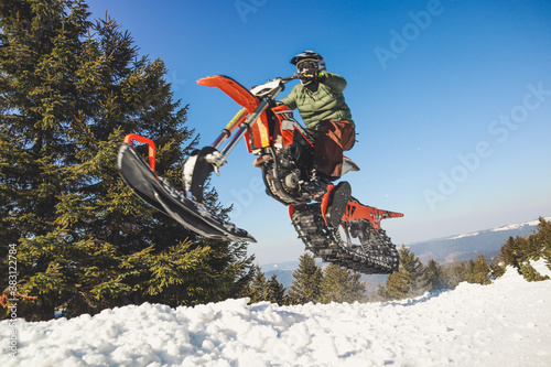 Snowbike rider in mountain valley in beautiful snow powder. Snowdirt bike with splashes and trail. Snowmobile winter sport riding photo