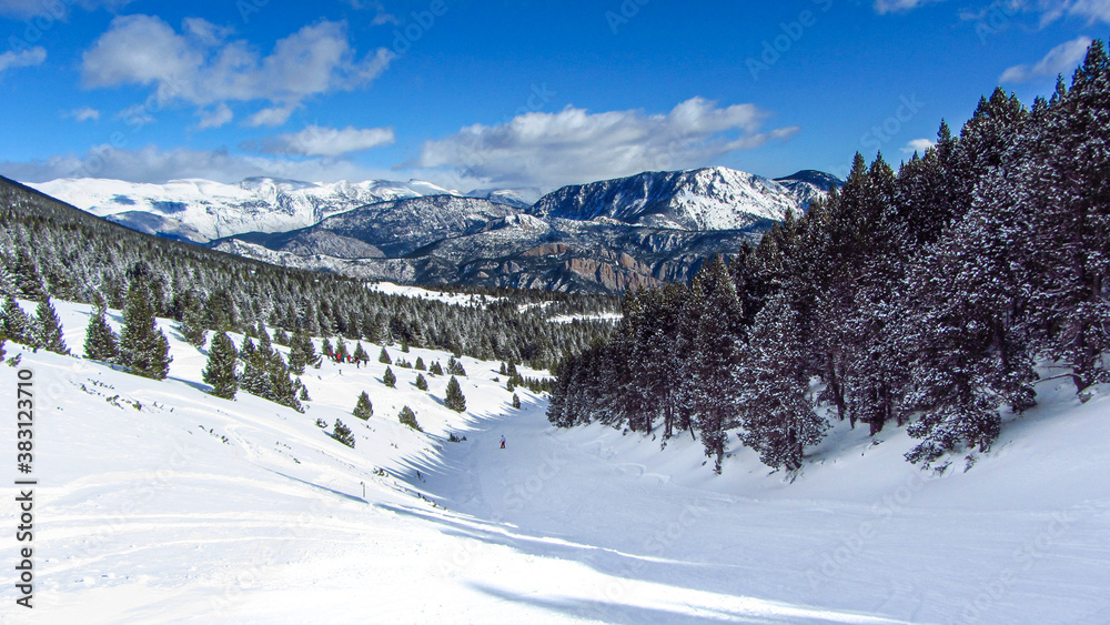 Beautiful snowy winter landscape in the Pyrenees with pine and fir trees. Winter sport with skiers skiing.