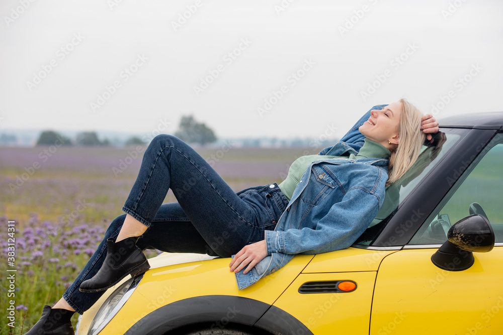Style blonde with a car near flowers filed in autumn time 
