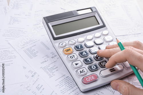 Unrecognizable businessman using calculator on desk office and writing make note with calculate about cost at home office. finance accounting concept. tax , shopping, cost management