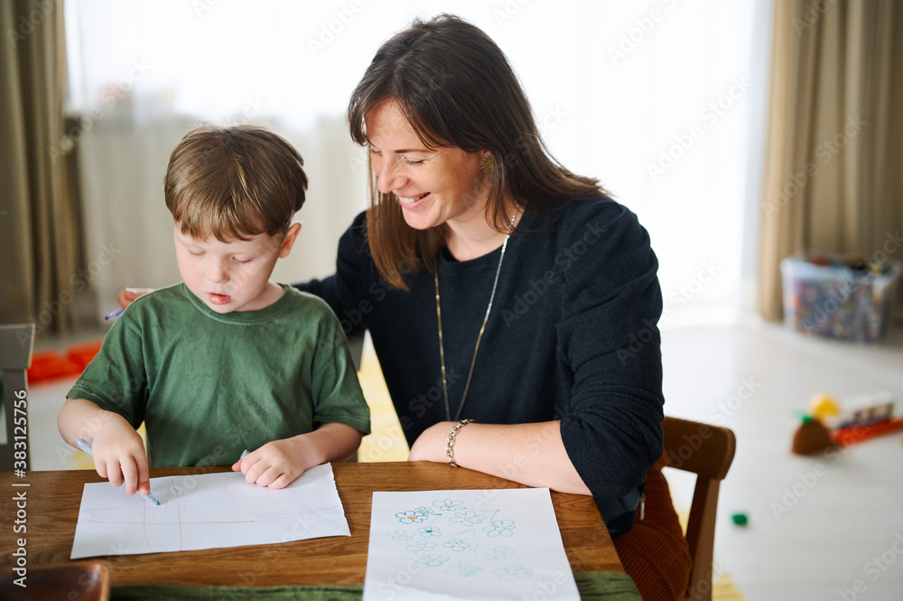 Happy family. Mother with little son painting and drawing together. Caucasian boy with his mother studying at home Happy family. Mother with little son painting and drawing together. Caucasian boy with his mother studying at home