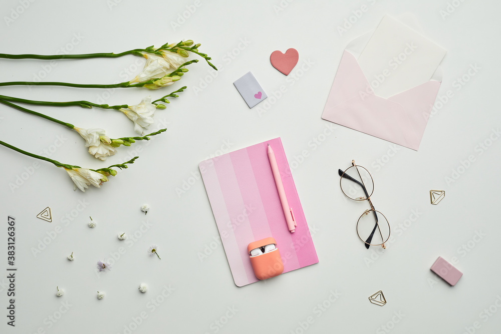 Minimal background composition of female themed stationary, accessories and eyeglasses on white table with floral decor, copy space Minimal background composition of female themed stationary, accessories and eyeglasses on white table with floral decor, copy space
