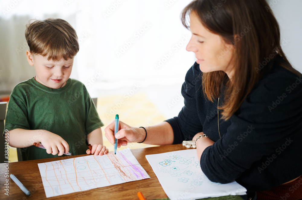 Happy family. Mother with little son painting and drawing together. Caucasian boy with his mother studying at home Happy family. Mother with little son painting and drawing together. Caucasian boy with his mother studying at home