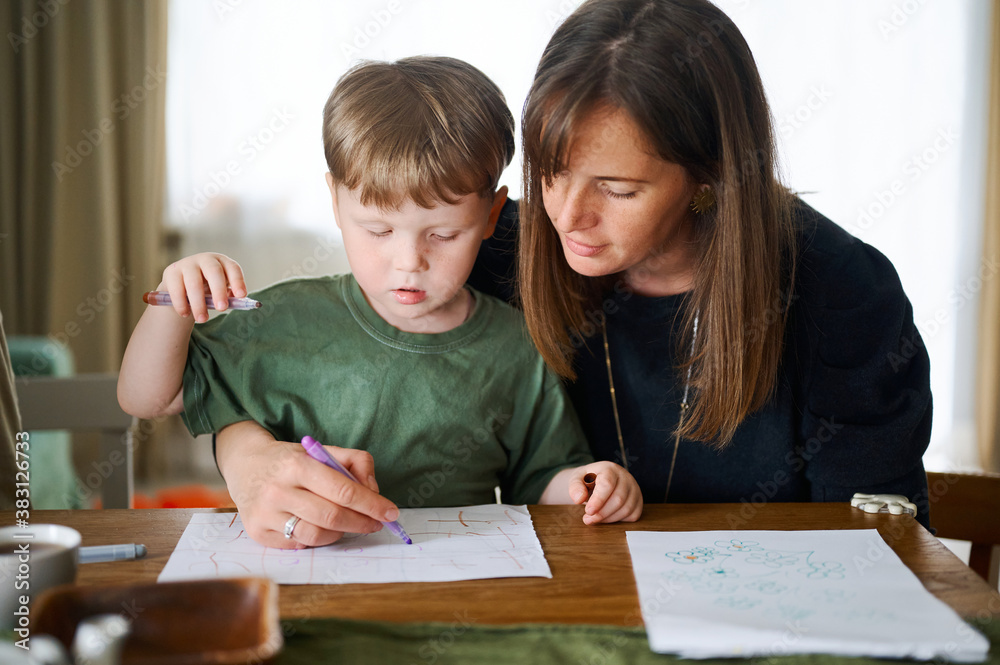 Happy family. Mother with little son painting and drawing together. Caucasian boy with his mother studying at home Happy family. Mother with little son painting and drawing together. Caucasian boy with his mother studying at home