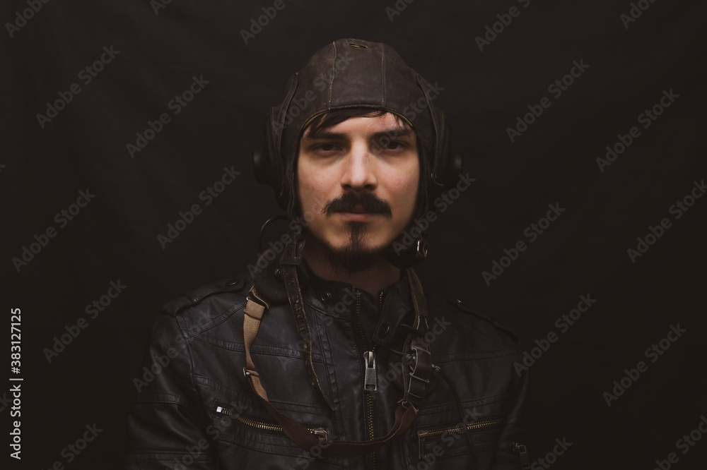 Male portrait in retro style. young man in the vintage aviation costume on the black background