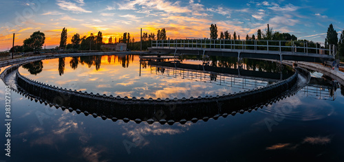 Modern sewage treatment plant. Round wastewater purification tanks at sunset.