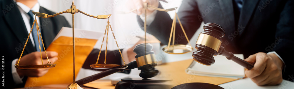 Business and lawyers discussing contract papers with brass scale on desk in office. Law, legal services, advice, justice and law concept picture with film grain effect Business and lawyers discussing contract papers with brass scale on desk in office. Law, legal services, advice, justice and law concept picture with film grain effect