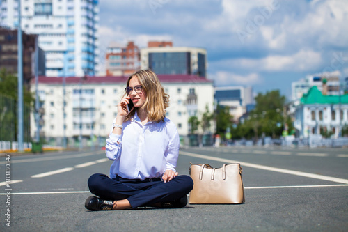 Young beautiful business woman sitting in the city square photo