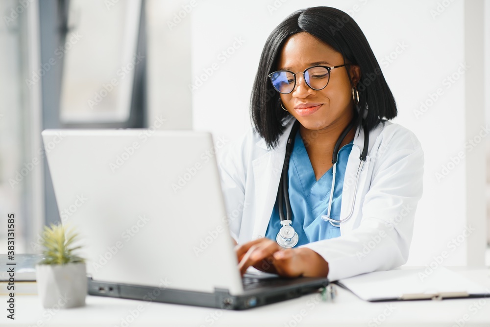 Young African-American doctor working on laptop in clinic