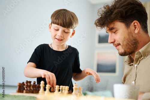 Father teaching son how to play chess. Concept of education and teaching.
