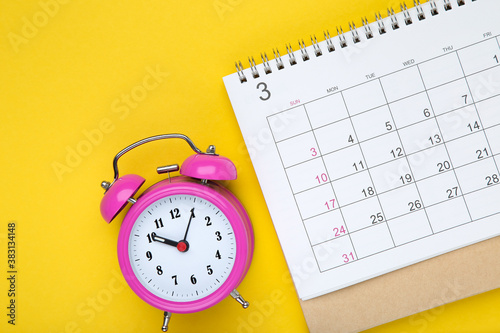 Calendar page with alarm clock on yellow background