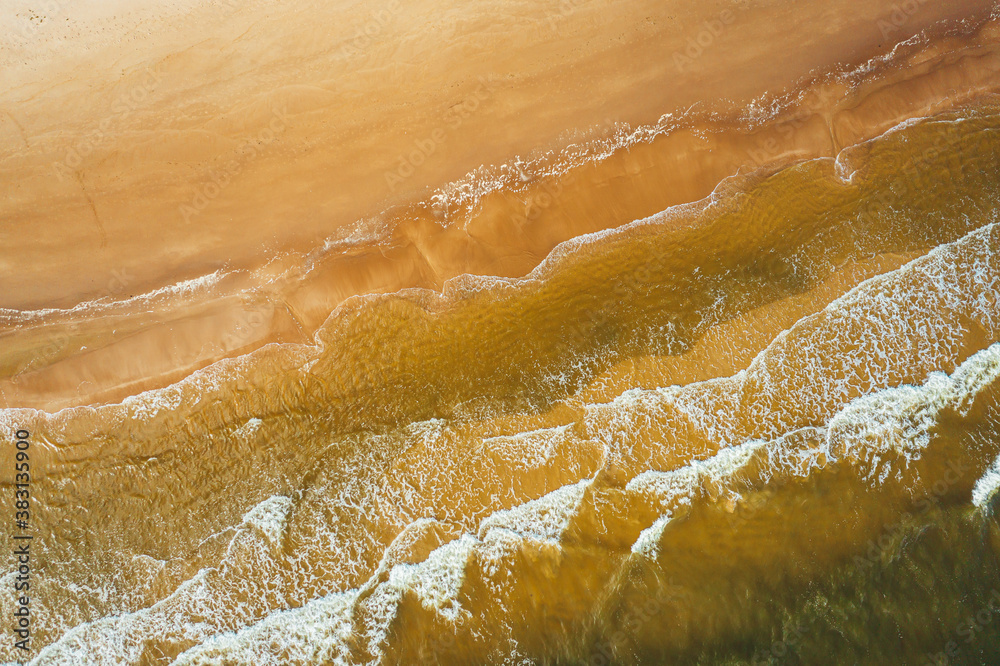 Aerial view from above on sea vawes , waves and foam crashing on the beach forming beautiful textures, patterns.