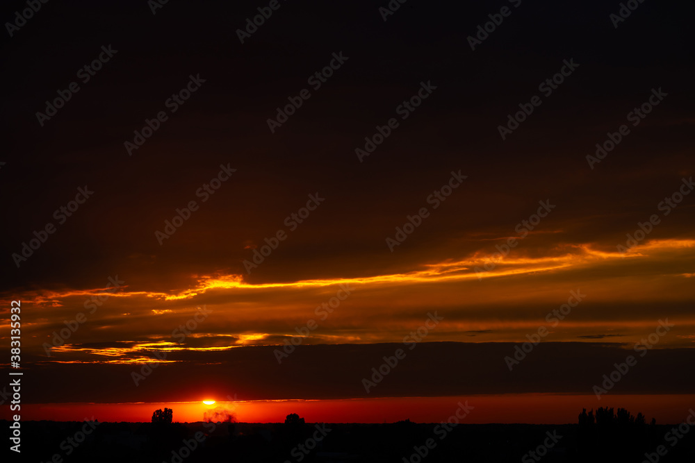 Fototapeta premium Heavy cloudy sky at sunset. Orange line of light between black clouds. A landscape of beautiful nature