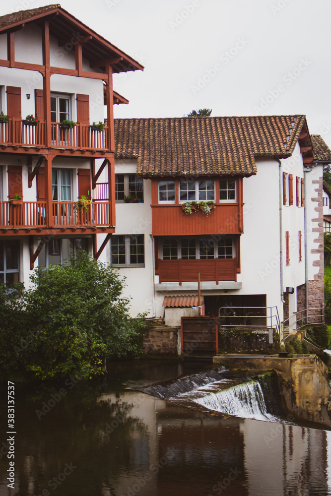 Fototapeta premium Beautiful medieval houses on the river bank. Village in France on the river. Rural landmark with canal. Traditional facade of old cottage, France. Chilly view of french village. Medieval architecture.