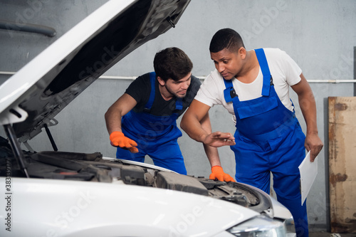 An repairer gives advice to a mechanic about repairing a car