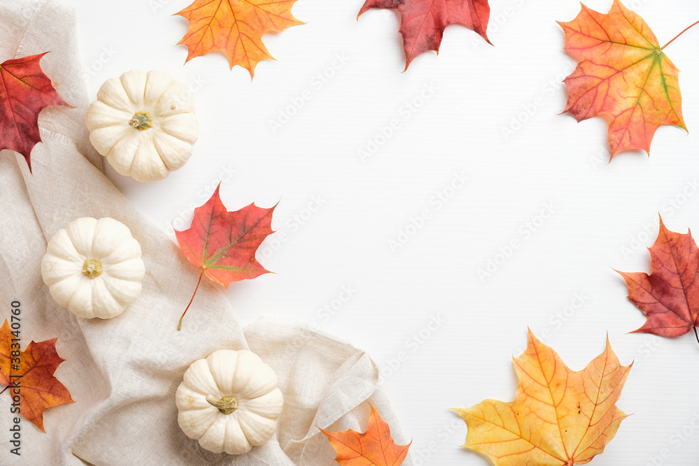 Autumn composition. Frame made of pumpkins, colorful maple leaves, beige fabric on white background. Flat lay, top view. Autumn fall, harvest, thanksgiving concept.