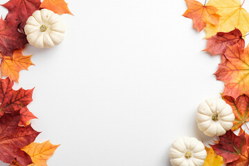 Autumn frame. Colorful maple leaves and pumpkins on white background. Flat lay, top view, copy space. Autumn fall, harvest, thanksgiving concept.