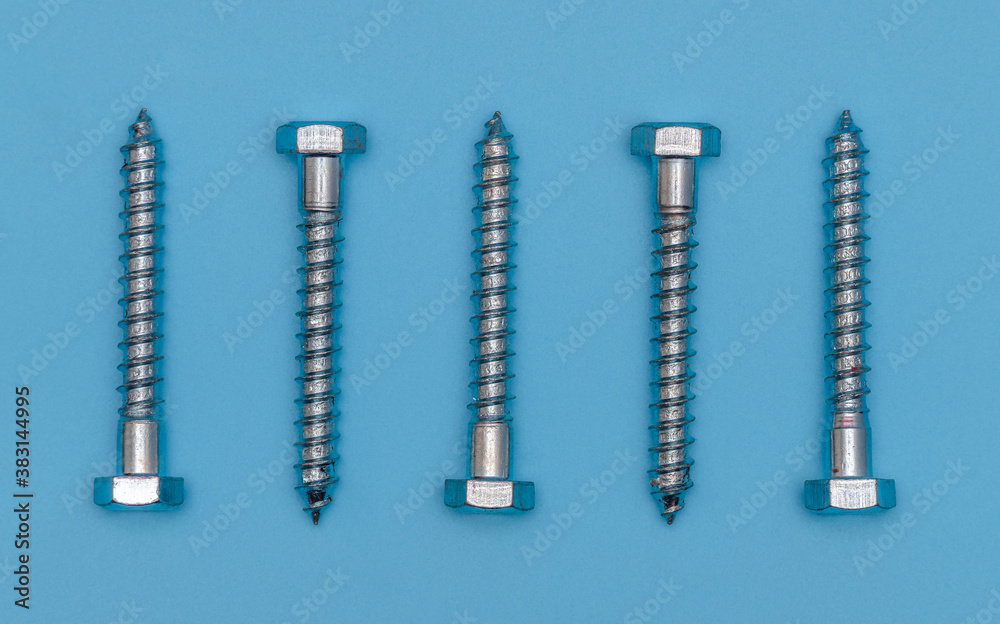 Hexagonal head screw aligned in a horizontal row on light blue background. Metric Hexagonal Head Coach Screw Bright Zinc Plated. Hexagonal head screw aligned in a horizontal row on light blue background. Metric Hexagonal Head Coach Screw Bright Zinc Plated.